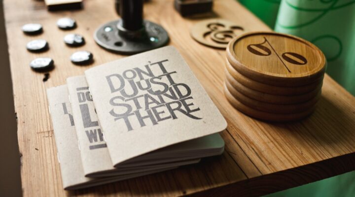 Notebook saying "Don't Just Stand There" on table